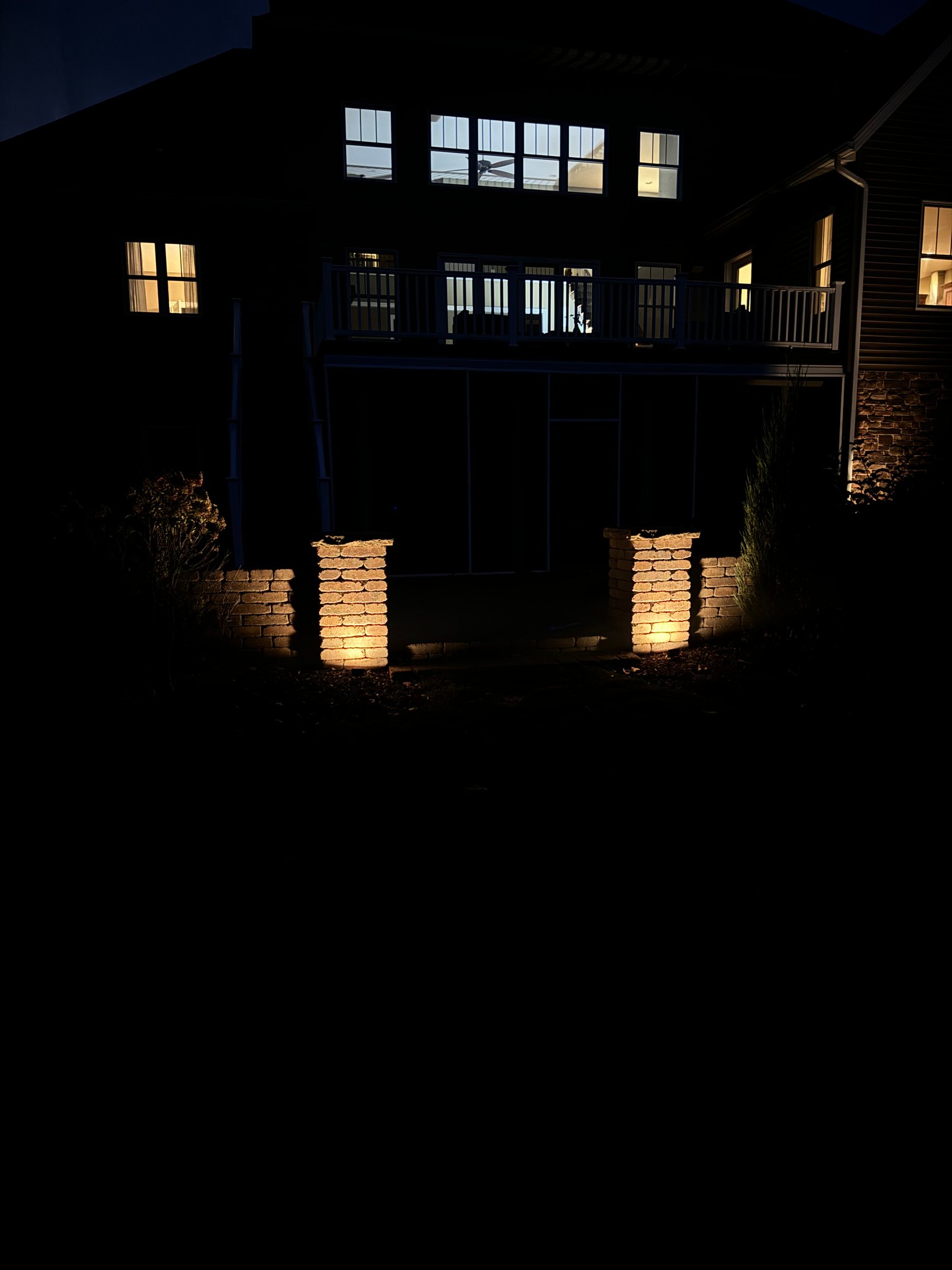 Uplit stone columns framing a covered backyard patio at night