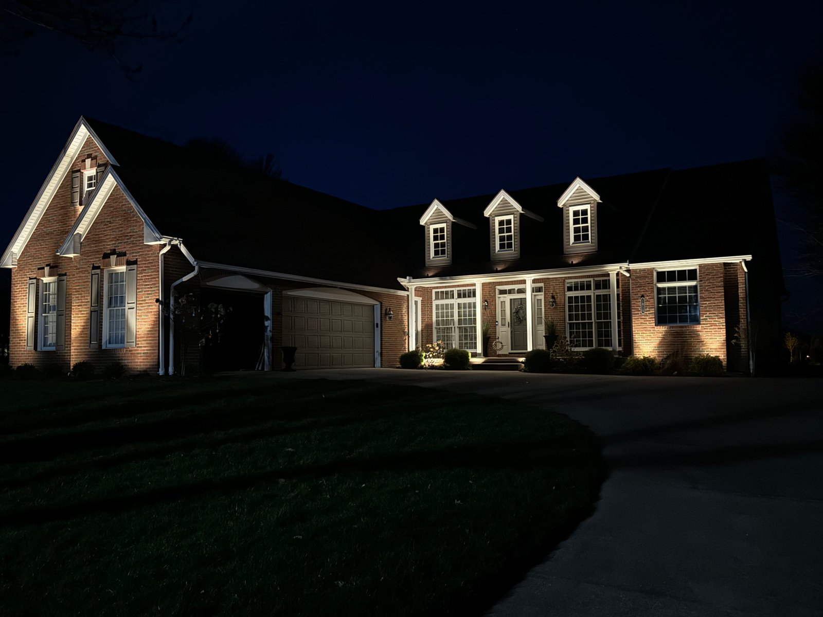 Home exterior at night with landscape lighting installed